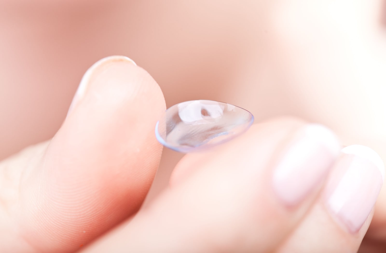 A close-up o a soft contact lens held at the tip of two human fingers. In more mild cases of dry eye, soft contact lenses are sometimes suitable