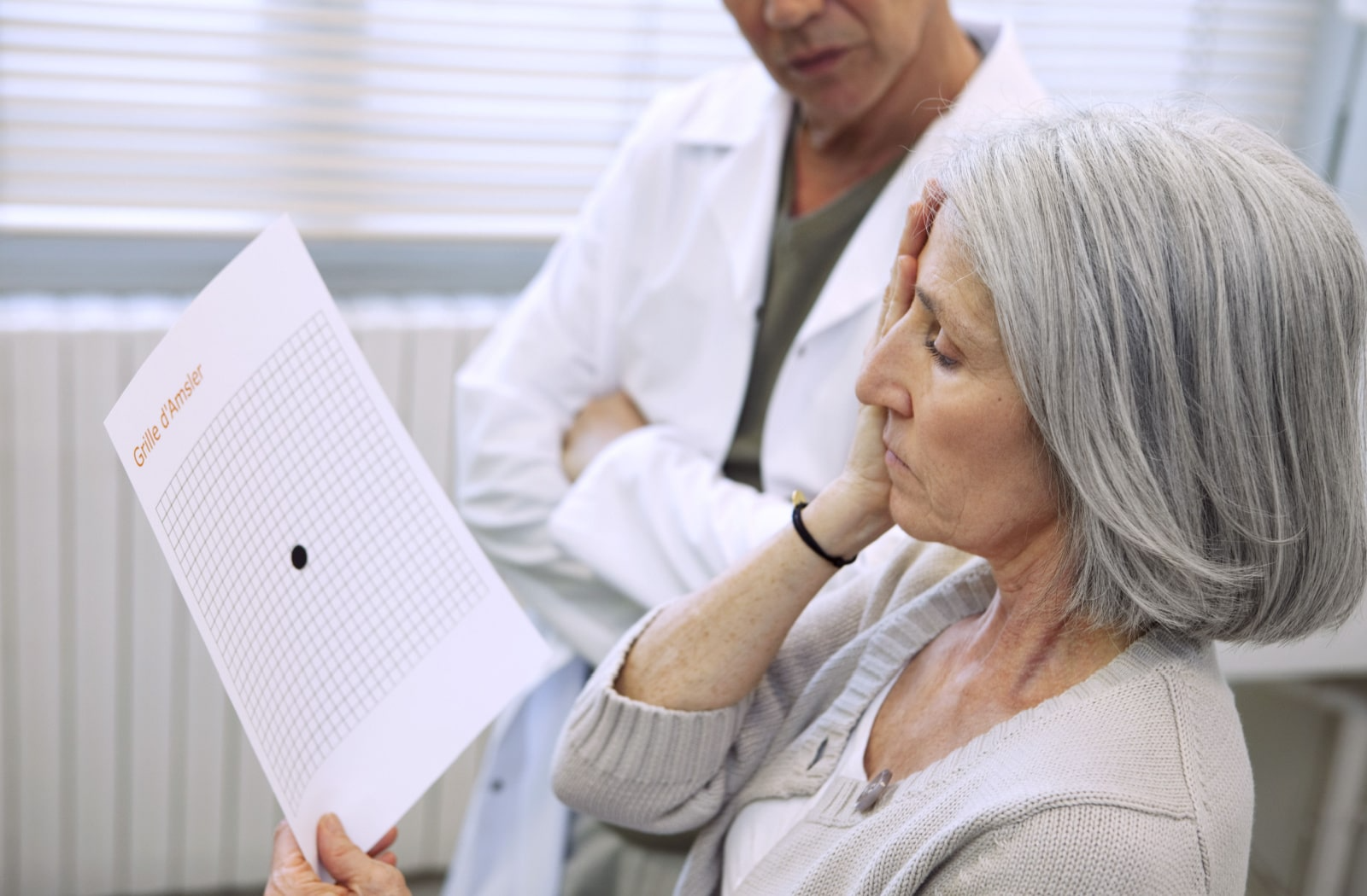 A woman performs an age-related macular degeneration test with her optometrist.