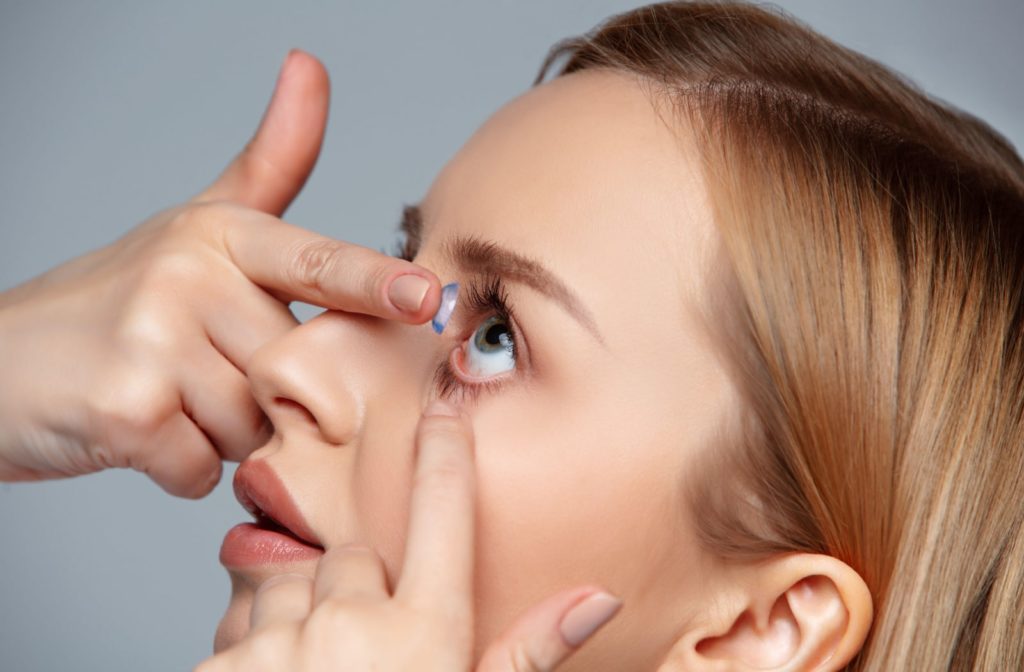 A close-up of a woman inserting a contact lens