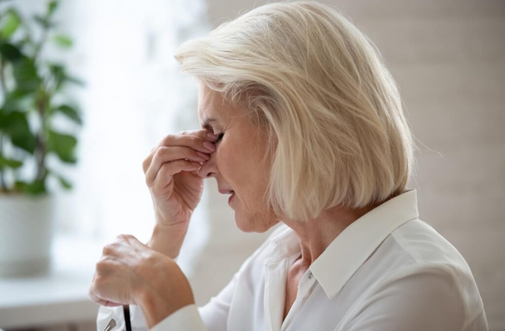 A person is rubbing the eye in discomfort while holding a pair of glasses, illustrating the physical strain and blurriness associated with dry eye syndrome.
