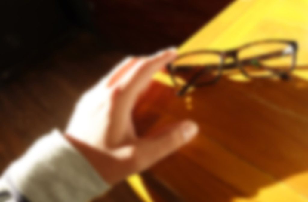 A point of view of a person with blurry vision reaching out towards their glasses.