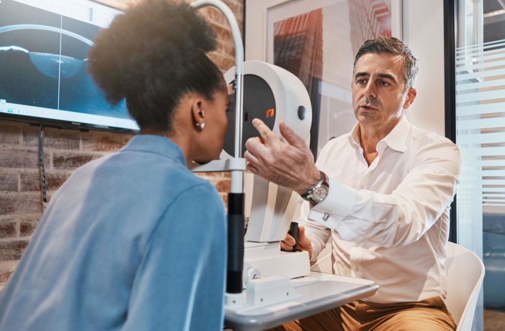 An optometrist examining a female patient's eyes to diagnose the cause of her symptoms.