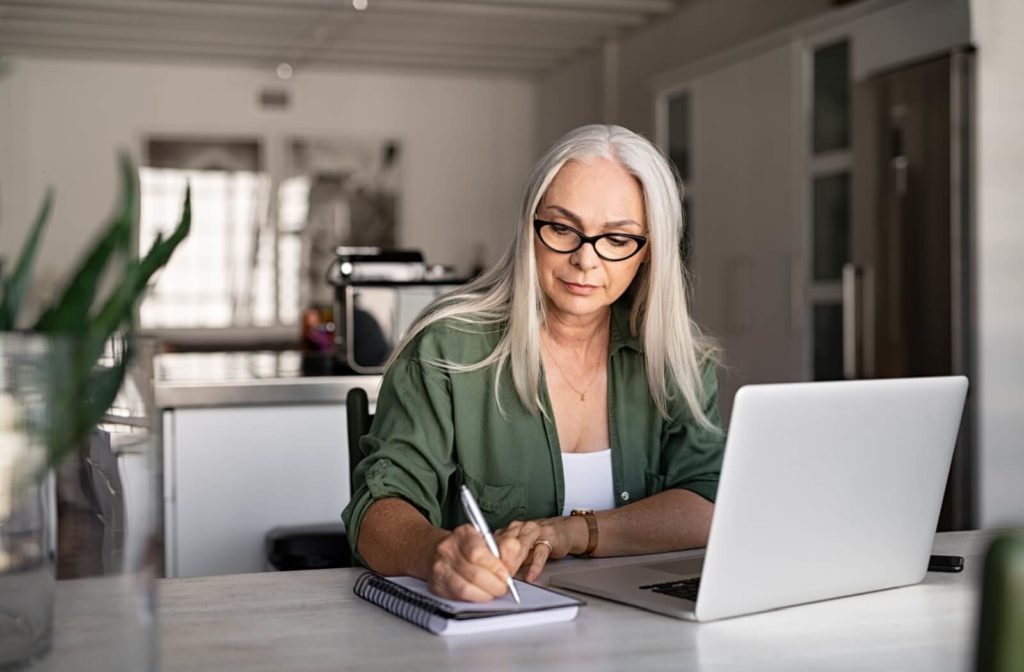 A woman wearing glasses sitting at her computer researching keratoconus