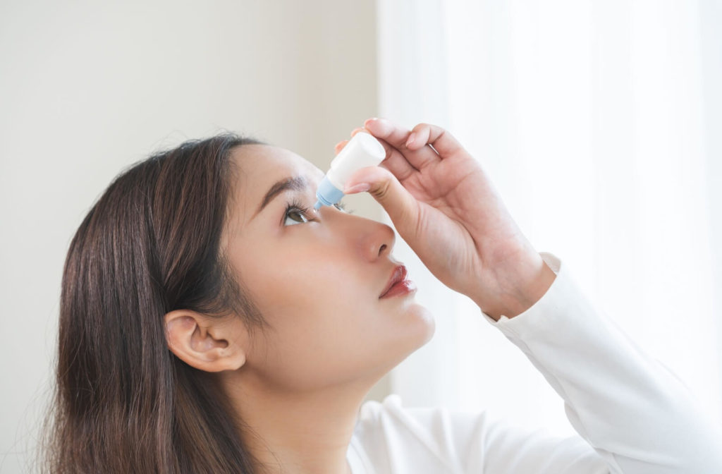 Person carefully inserting eye drops into the eye with one hand in a bright modern home setting