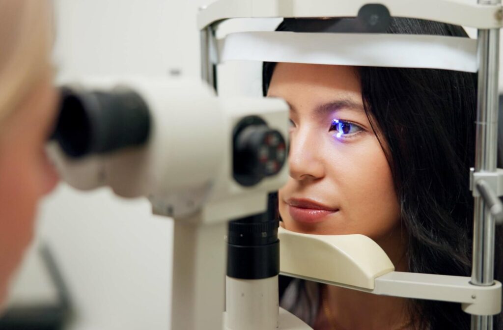 An optometrist examines their patient's eye with a slit lamp during an eye exam.