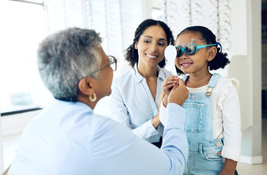 A young person smiles as she undergoes an eye exam.