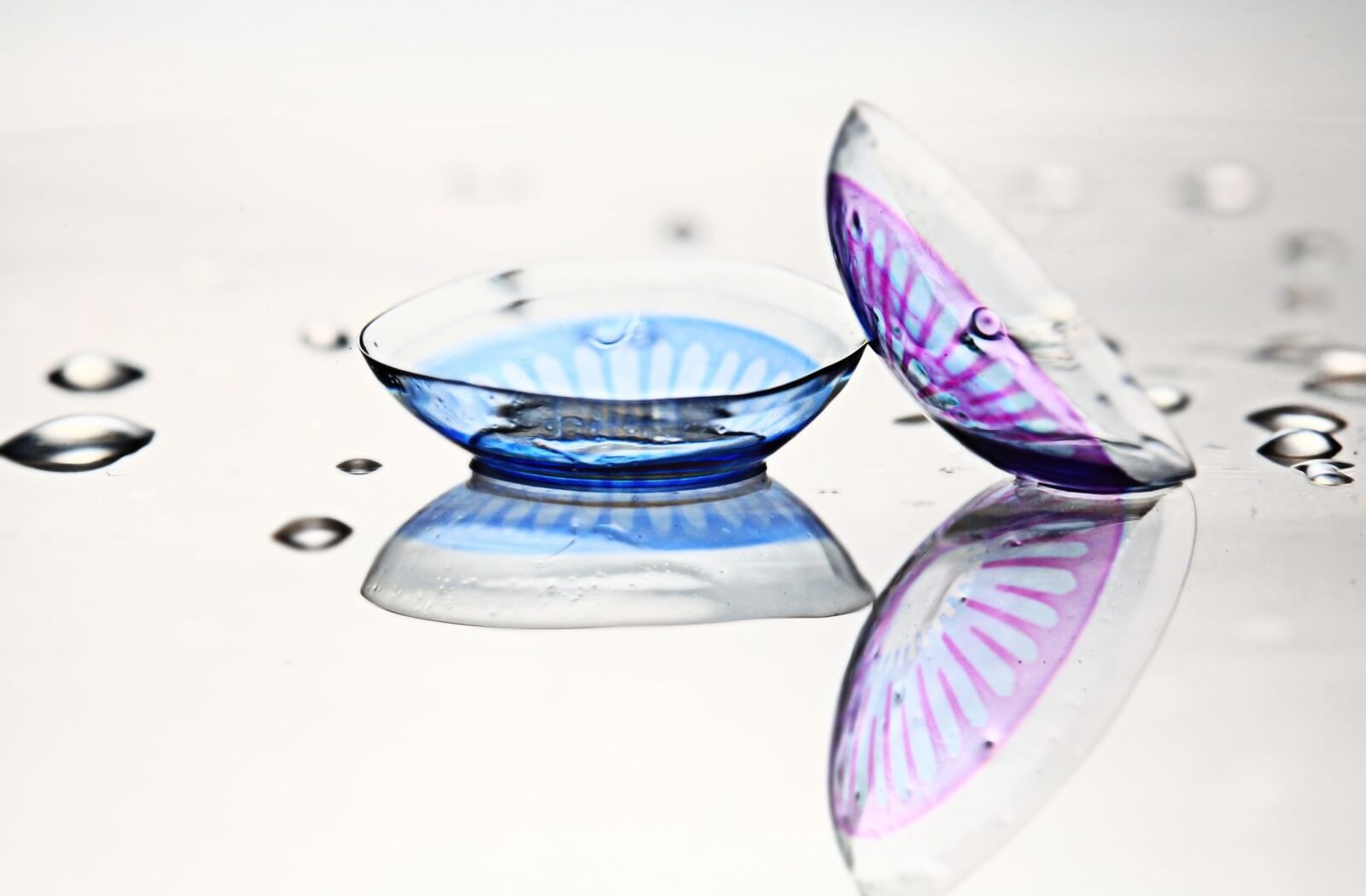 Close-up of two coloured contact lenses, one blue and one purple.