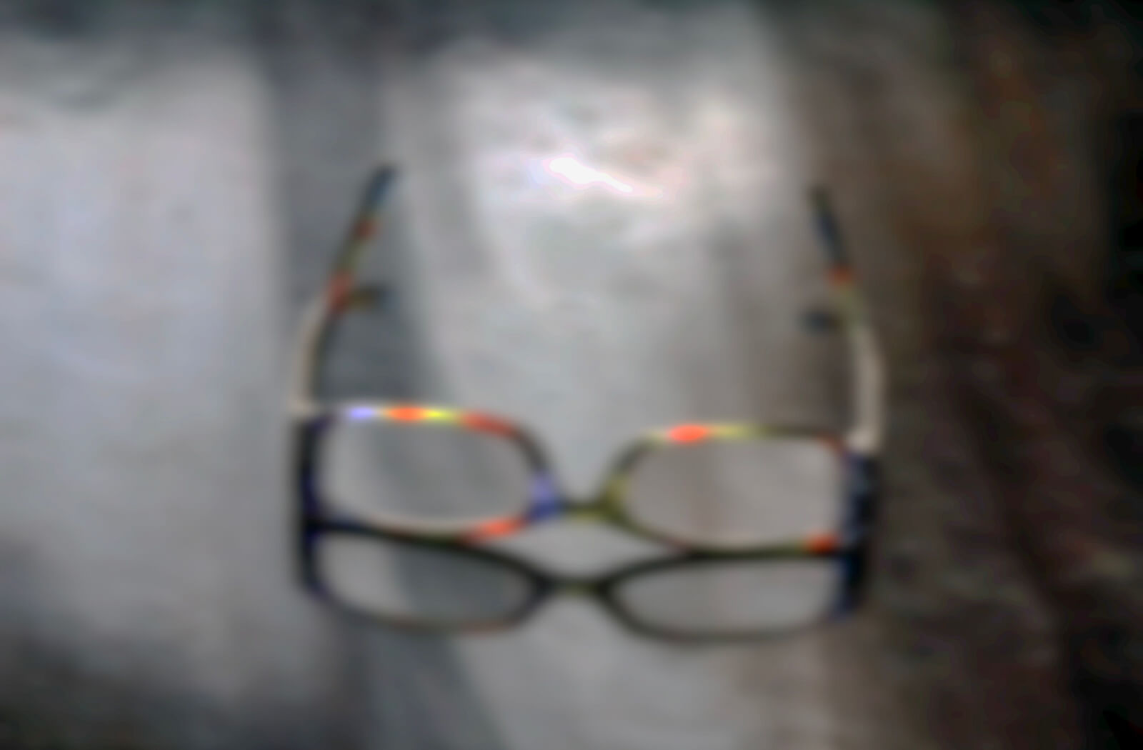 A heavily blurred image of colorful eyeglasses, visually representing the symptom of blurred vision often caused by chronic dry eyes.
